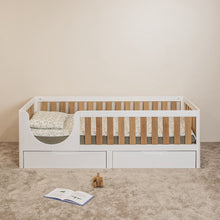Front view of EZRA Montessori toddler bed with white frame, oak veneer rails and storage drawers