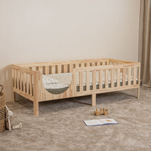 Angled view of EZRA Montessori toddler bed on legs with rounded entrance and natural pine safety rails