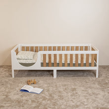 Front view of EZRA Montessori toddler bed on legs with white frame and oak veneer safety rails