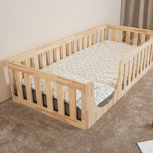 Elevated angled view of EZRA Montessori toddler floor bed with rounded entrance and natural pine safety rails