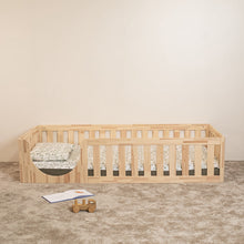 Front view of EZRA Montessori toddler floor bed with low rounded entrance and natural pine safety rails