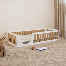 Angled view of EZRA Montessori toddler floor bed with white pine frame, oak veneer safety rails and rounded entrance