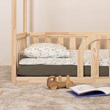 Detail of rounded entrance, mattress and natural wood frame on Montessori house floor bed