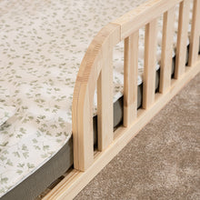 Close-up of rounded opening and smooth natural pine safety rail on Montessori house floor bed