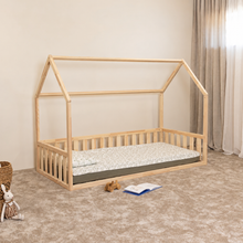 Angled view of Montessori house floor bed for toddlers with wooden house frame and open front side