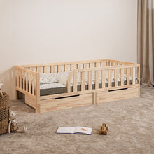 Angled view of Montessori toddler bed with rounded opening and closed storage drawers