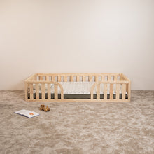Front view of Montessori toddler floor bed with rounded middle opening and natural wood safety rails