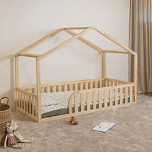 Angled view of NOLRI Montessori house floor bed for toddlers with rounded opening and natural pine safety rails