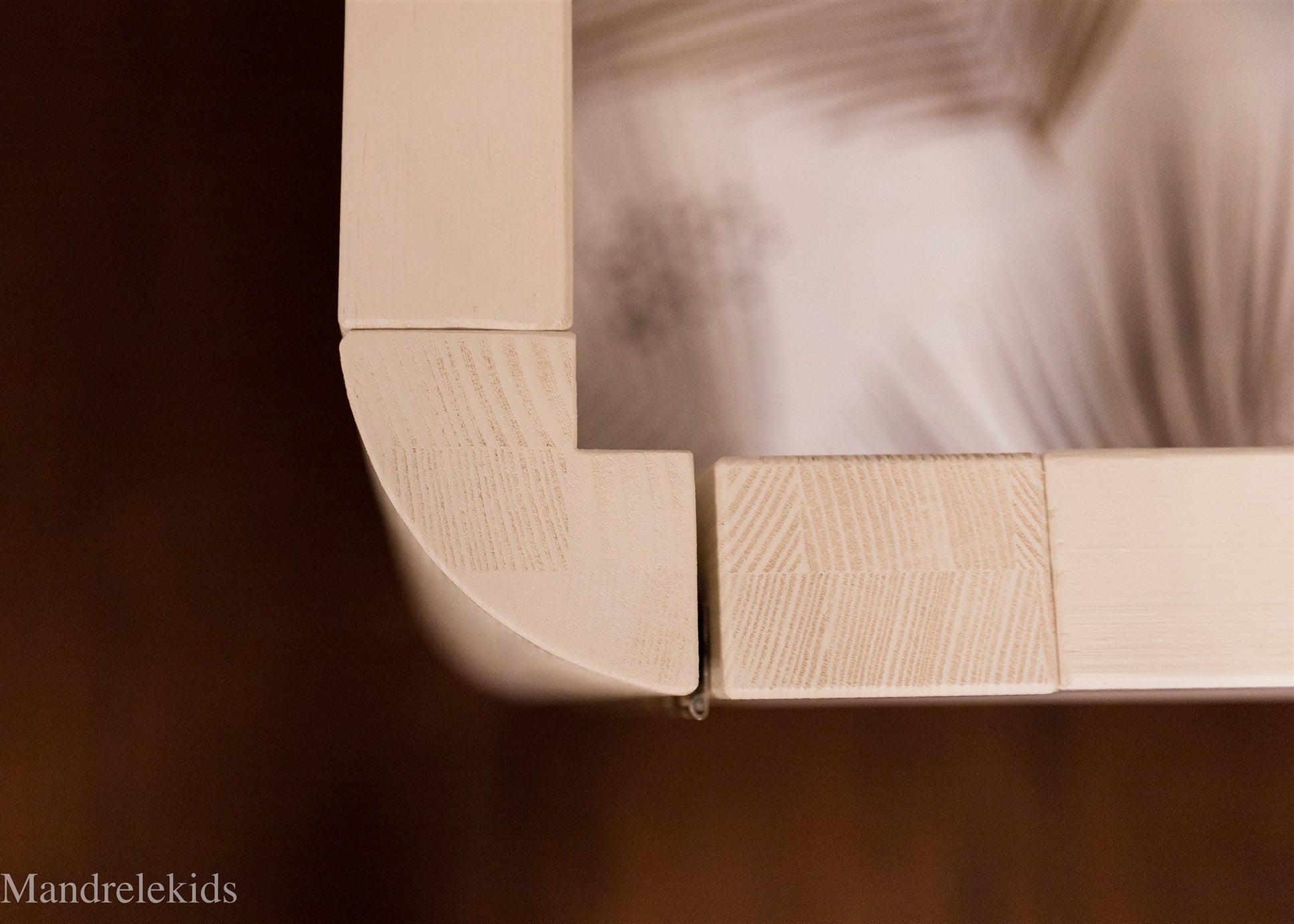Rounded corner detail of a wooden Montessori toddler bed with doors