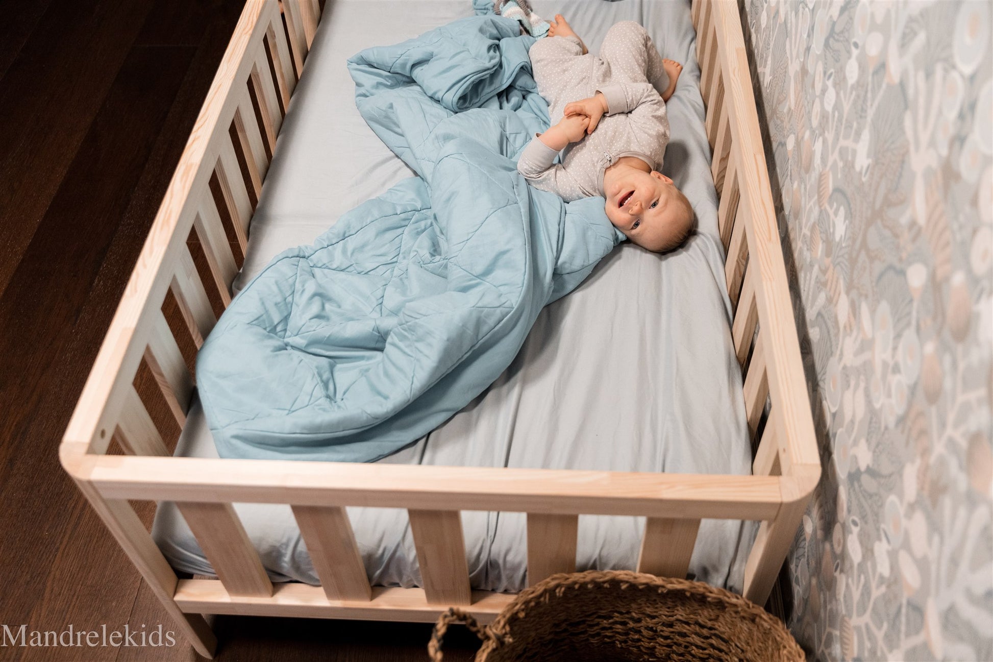 Top view of a wooden Montessori toddler bed with rails and a child lying on the mattress