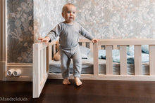 Wooden Montessori toddler floor bed with door and a child stepping out